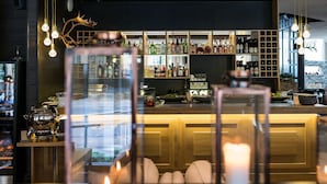 Un espace bar avec un comptoir en bois, des étagères remplies de bouteilles d’alcool et une vue sur l’extérieur.
