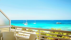 Un balcon avec vue sur l’océan, plusieurs bateaux et une chaise.