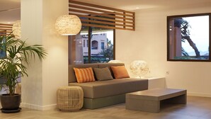 Un salon moderne avec un canapé, un pouf et une plante en pot.
