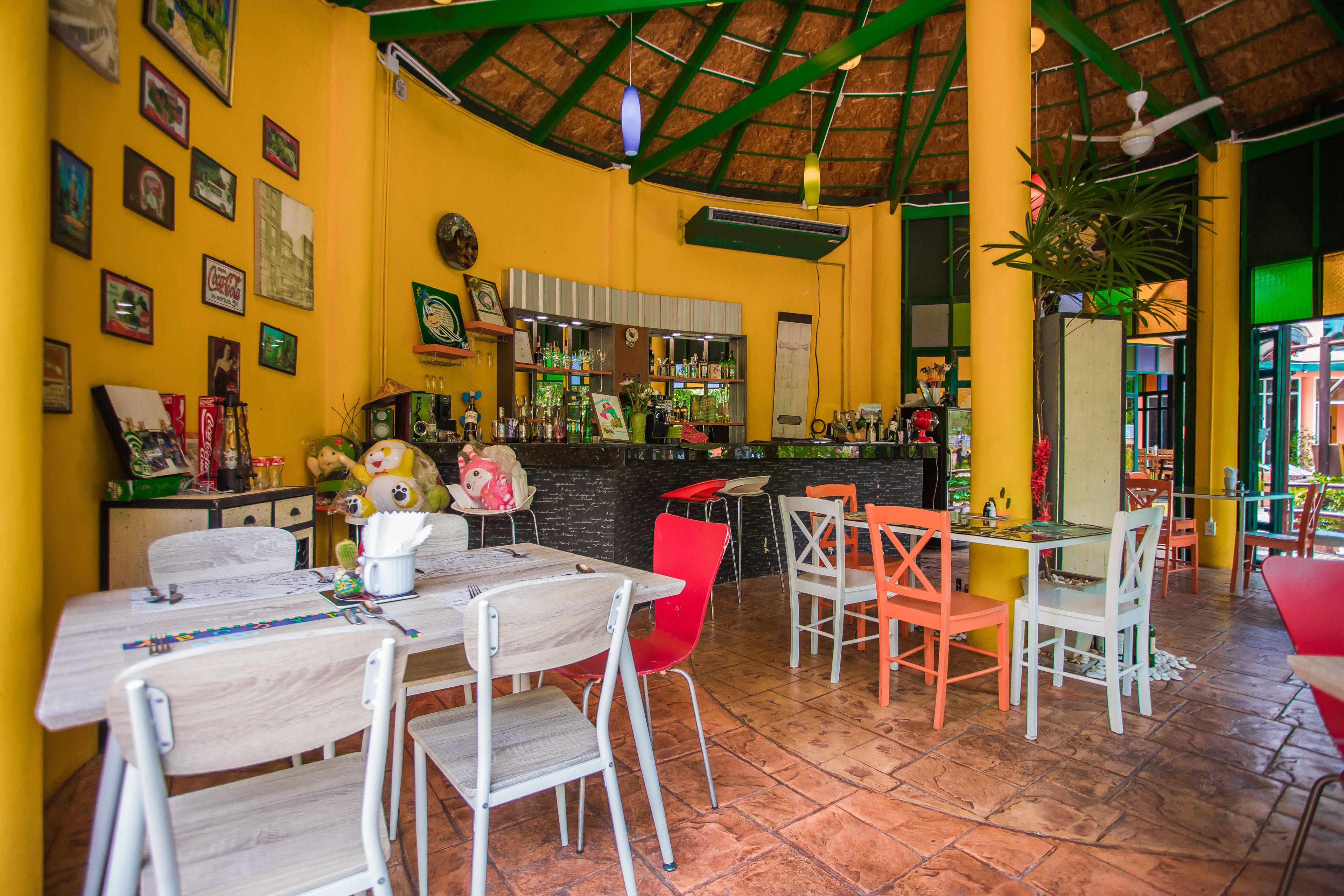 A restaurant with a thatched roof, yellow walls, and a variety of seating including tables and chairs.