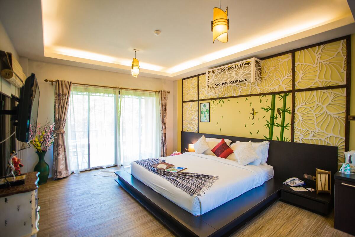 A hotel room with a large bed, bedside tables, a desk, and a view of the outdoors.