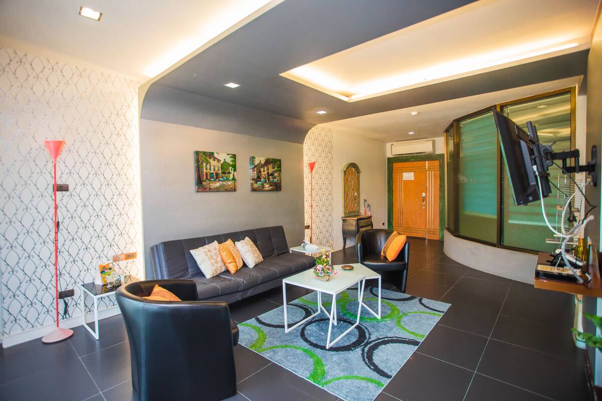 A modern living room with a sofa, armchairs, a coffee table, and a patterned rug.