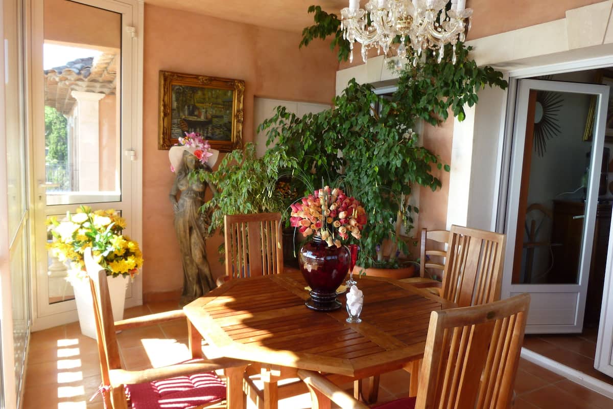 Un coin repas avec une table en bois, des chaises, un vase de fleurs et un lustre.
