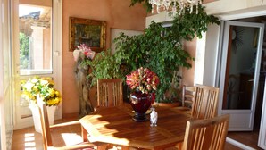 Un comedor con mesa de madera, sillas, un jarrón de flores y una araña.