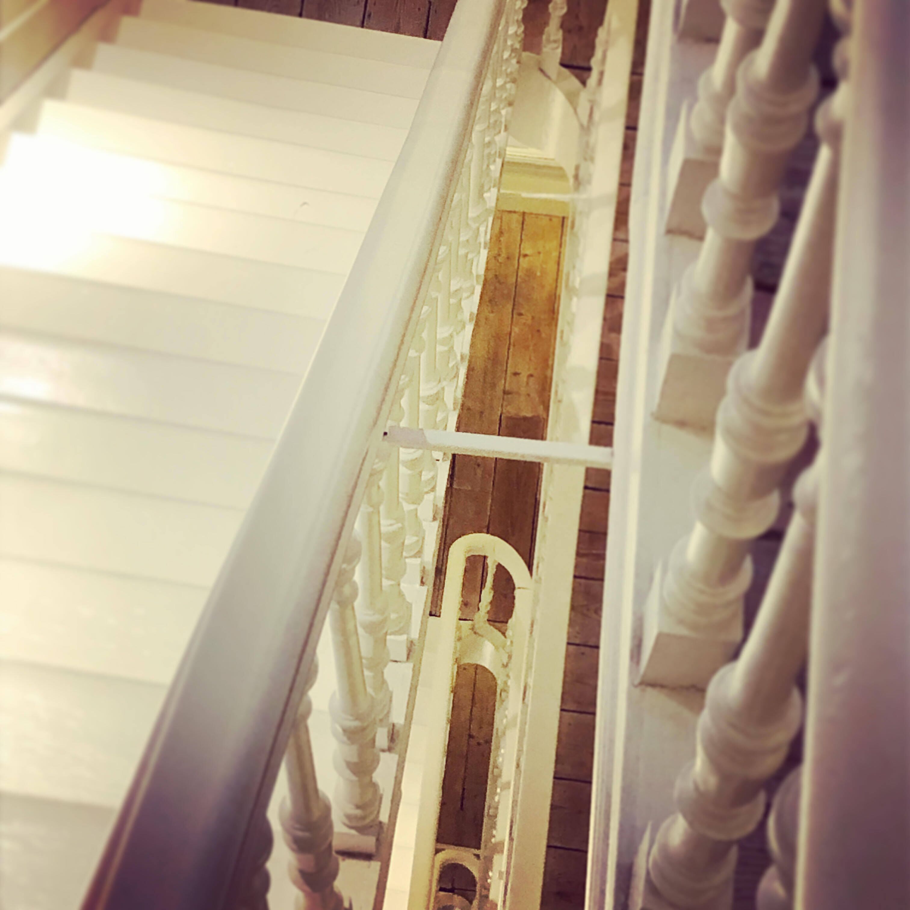 A staircase with white balustrades and a wooden handrail.