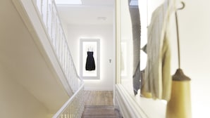 Een trap met witte leuningen die leidt naar een kamer met een lijstfoto en een hanglamp.