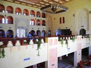 A spacious lobby with multiple levels, arched balconies, and a central chandelier. - Djerba Castille Hotel (Aghir)
