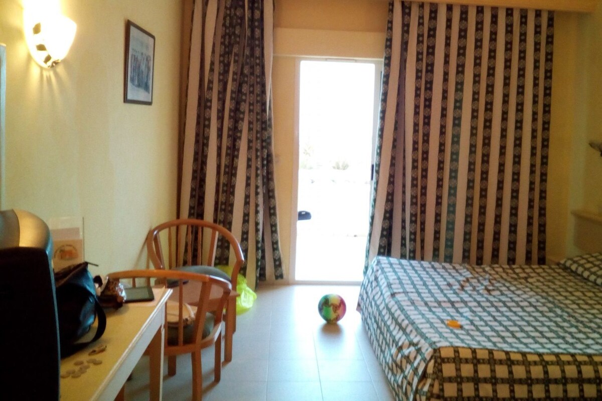 A hotel room with a bed, a desk, a chair, and a window with curtains.