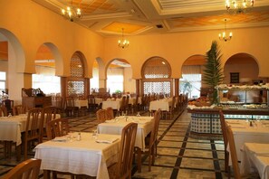 Ein Essbereich mit gedeckten Tischen für Gäste, mit einem zentralen Buffet und einer Auswahl an Speisen.