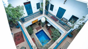 A courtyard with a swimming pool, potted plants, and blue doors. - Riad Azalia (Marrakech)