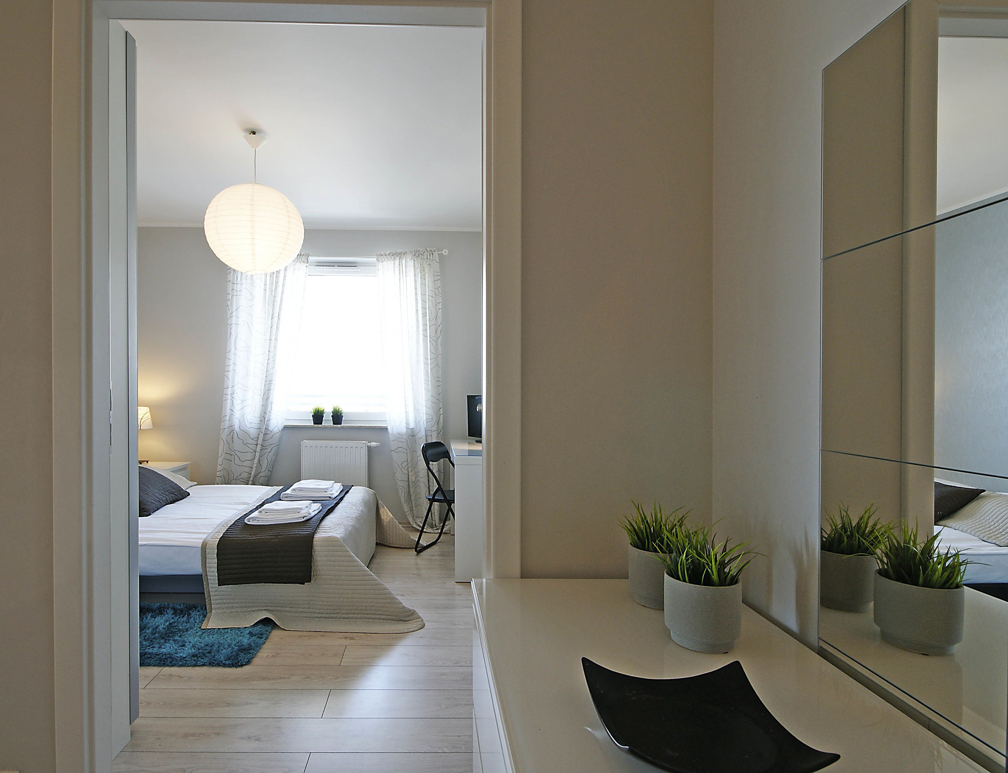 A modern bedroom with a bed, bedside table, lamp, and a view of the bathroom.