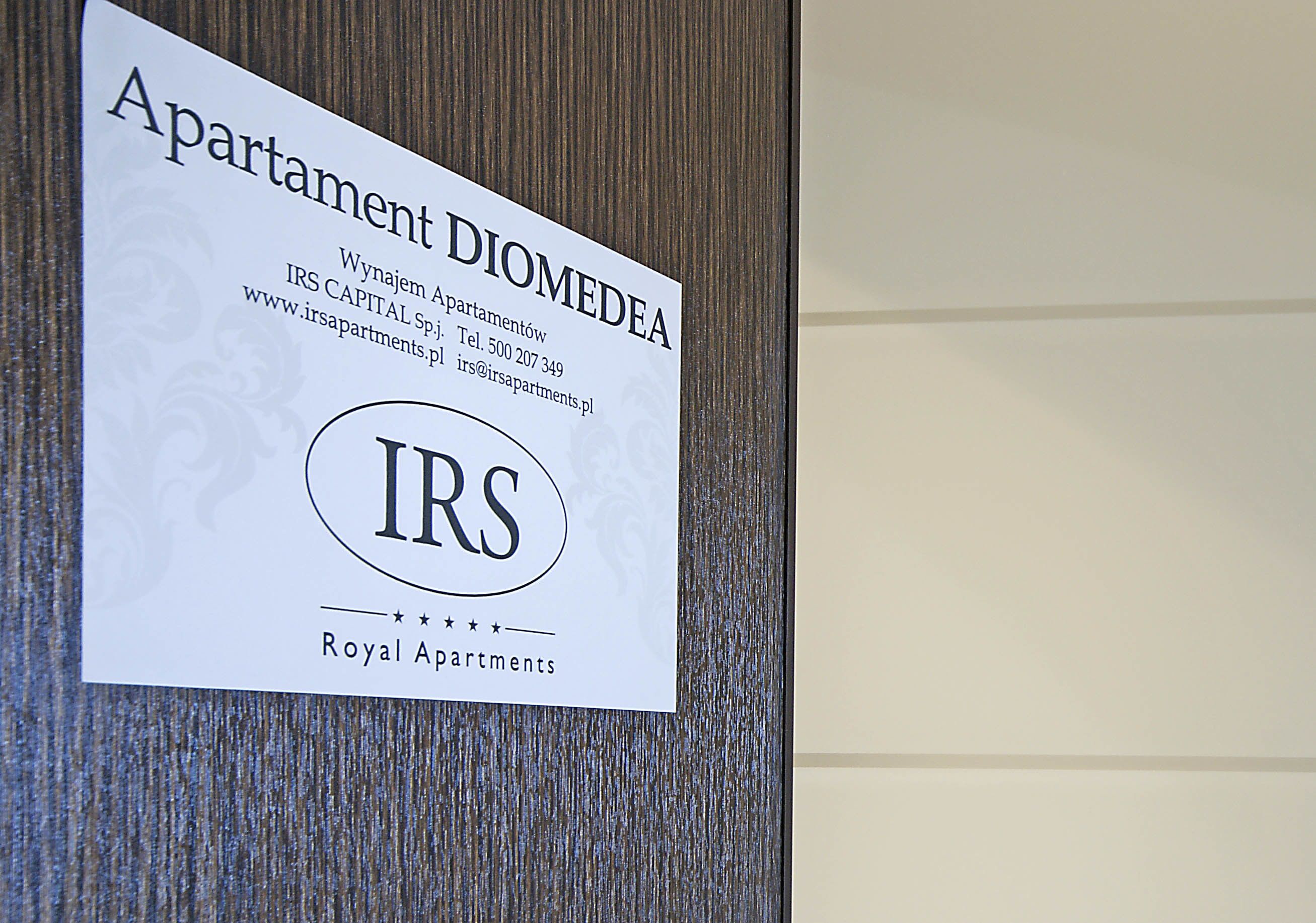 Placa com o nome 'Apartment DIOMEDEA', informações de contato e o logotipo 'IRS Royal Apartments'.
