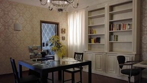 A dining area with a table and chairs, a bookshelf, and a chandelier. - B&B Santa Bibiana (Rome)