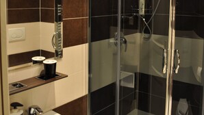 A modern bathroom with a glass-enclosed shower, a white sink, and a mirror above it. - B&B Santa Bibiana (Rome)