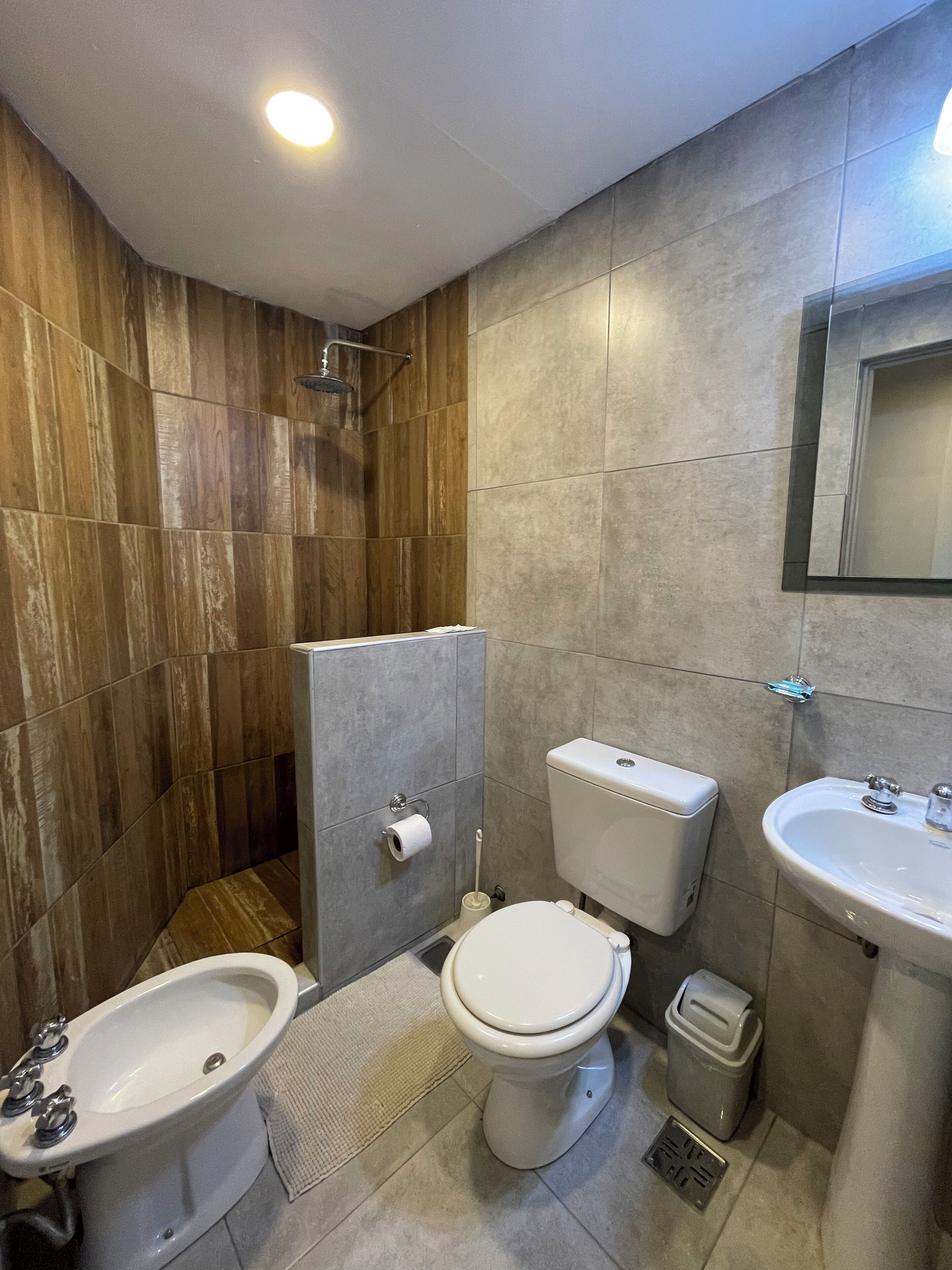 A bathroom with a bidet, toilet, sink, and shower.
