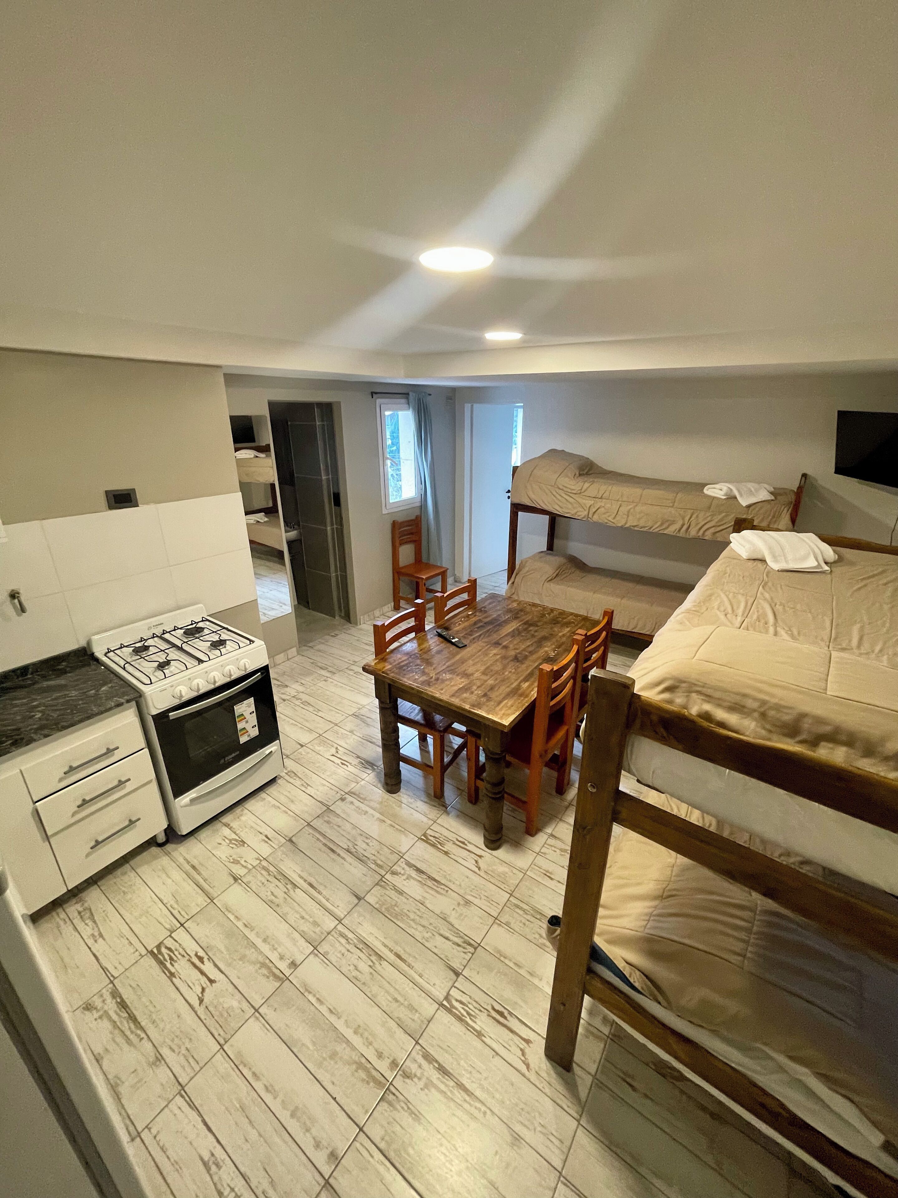 A compact room with a kitchenette, a dining table, and two bunk beds.