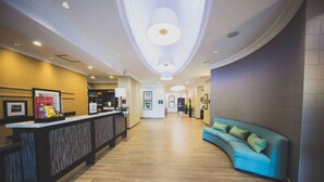 A hotel lobby with a reception desk, a blue sofa, and a modern ceiling design. - Hampton Inn & Suites by Hilton Bolton (Caledon)