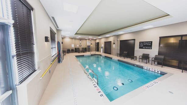 An indoor swimming pool with clear water, marked depth lines, and a lifeguard sign. - Hampton Inn & Suites by Hilton Bolton (Caledon)