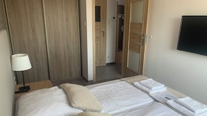 A hotel room with a bed, a bedside table with a lamp, a wardrobe, and a mirror. - IRS ROYAL APARTMENTS - IRS Aviator (Gdansk)