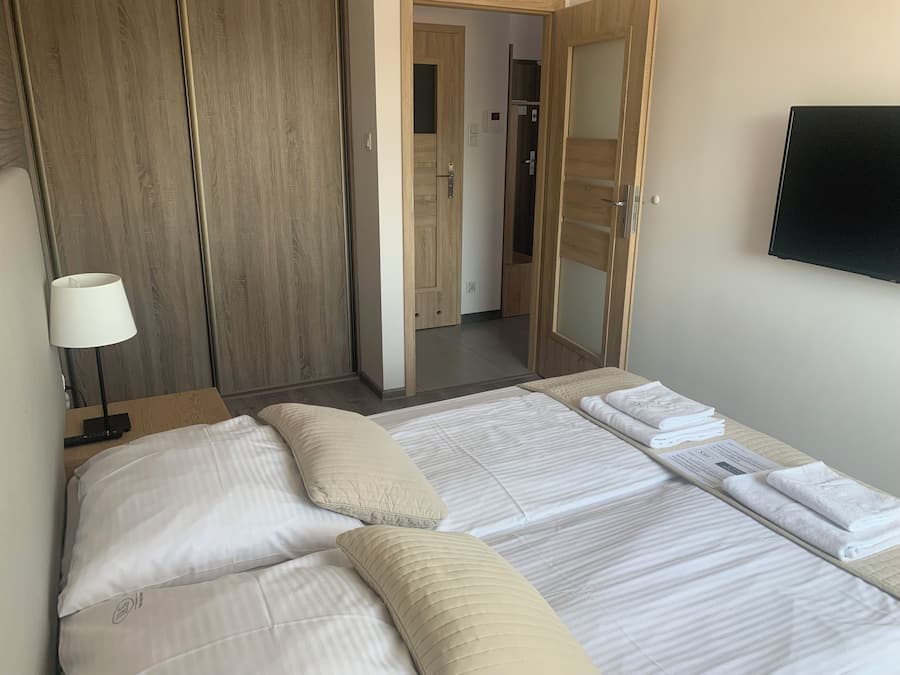 A hotel room with a bed, a bedside table with a lamp, a wardrobe, and a mirror.