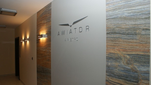 A hallway with a wall-mounted sign reading "AWIATOR 4 PIETRO" and a textured wall design. - IRS ROYAL APARTMENTS - IRS Aviator (Gdansk)