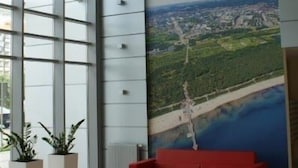 A modern lobby with a large mural of an airplane and landscape, red seating, and large windows. - IRS ROYAL APARTMENTS - IRS Aviator (Gdansk)