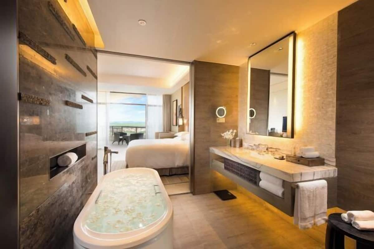 Relax in a spacious bathroom with a bathtub, dual vanity, and shower area, offering a view of the outdoors.