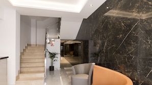 A modern lobby with a curved sofa, a staircase, and a marble wall. - Hostal Roca (Sant Antoni de Portmany)