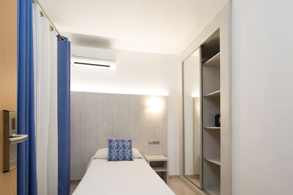 A hotel room with a bed, a nightstand, a wardrobe, and a shower area.