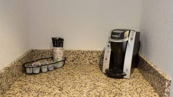 A kitchen counter with a Keurig coffee maker and a basket of coffee pods.