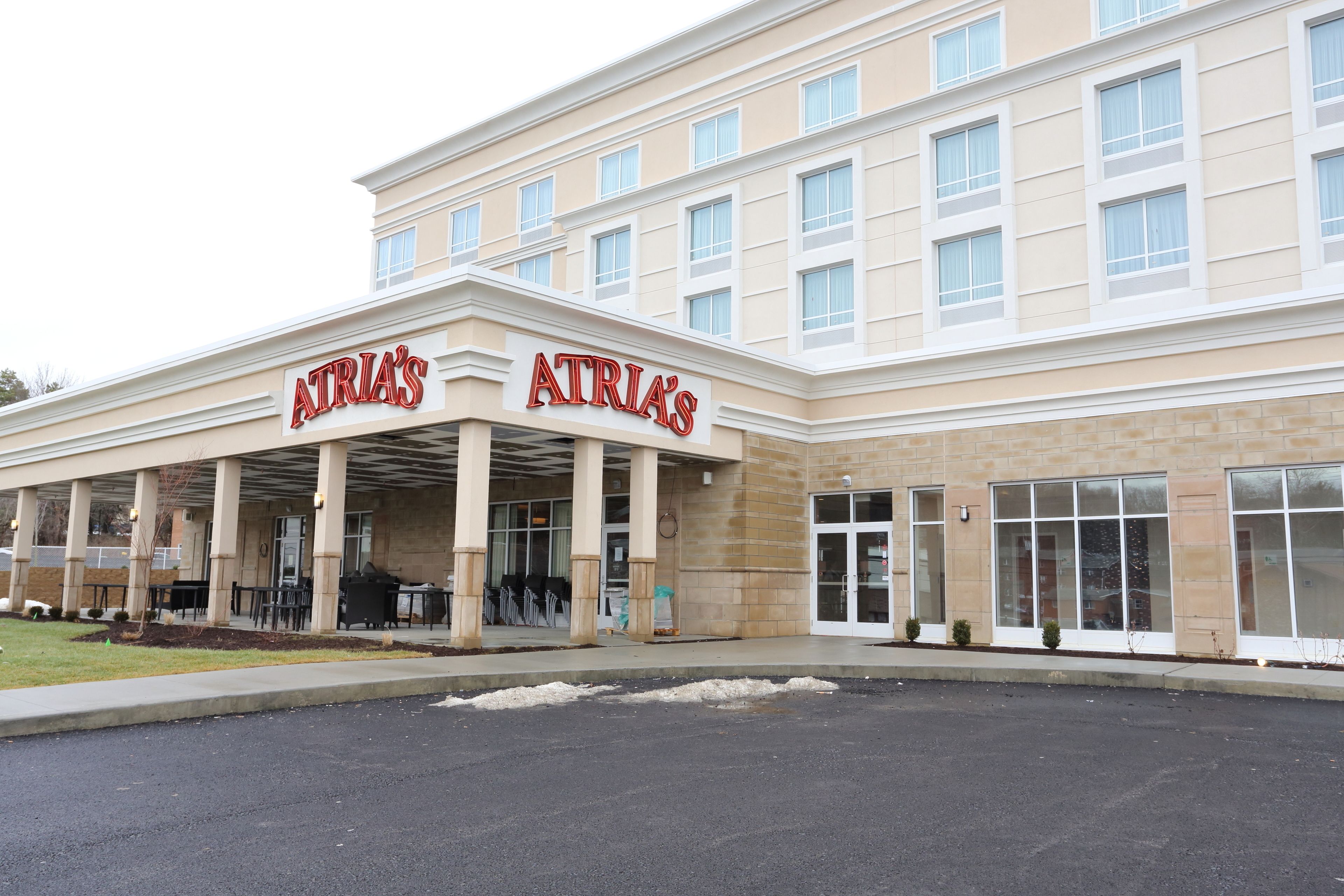 A hotel with a covered entrance, multiple windows, and a beige facade.