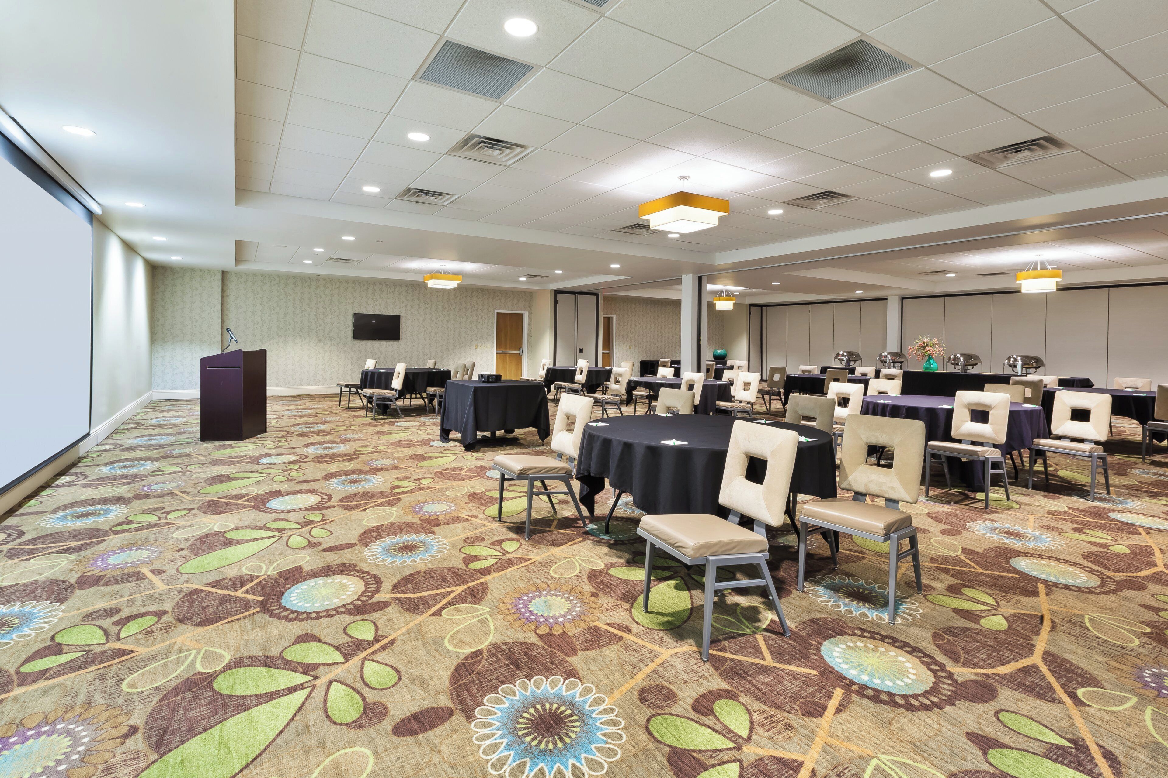 A conference room with a patterned carpet, round tables, and chairs.