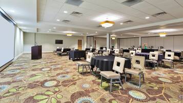 A conference room with a patterned carpet, round tables, and chairs.