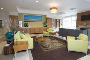 A modern lobby with a reception desk, seating area, and a large window providing natural light. - Holiday Inn Morgantown - University Area by IHG (Morgantown)