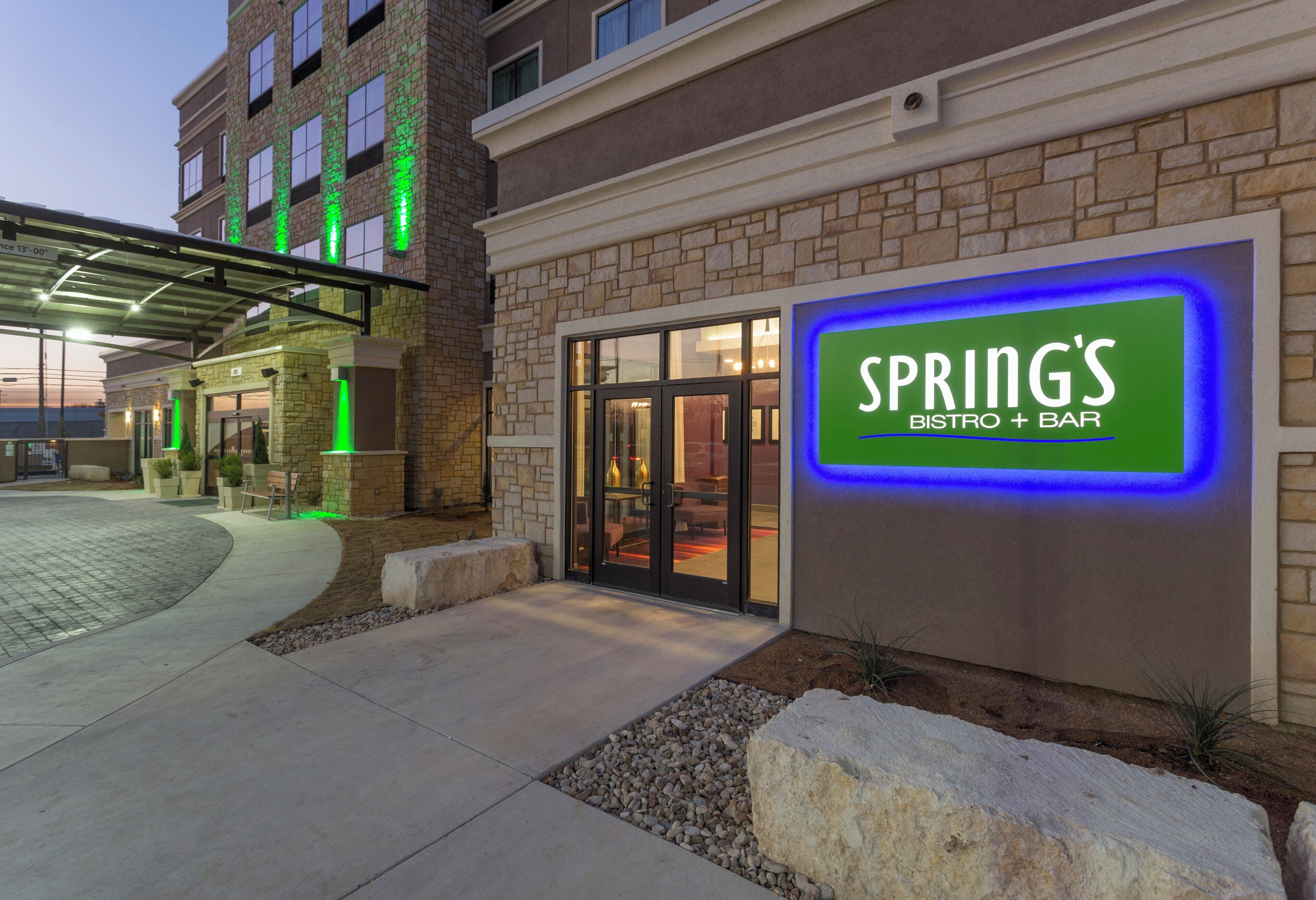A building with a sign for 'SPRING'S BISTRO + BAR' and a covered entrance area.
