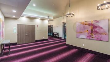 Un couloir d’hôtel avec un tapis violet, une porte, une table et un tableau accroché au mur.