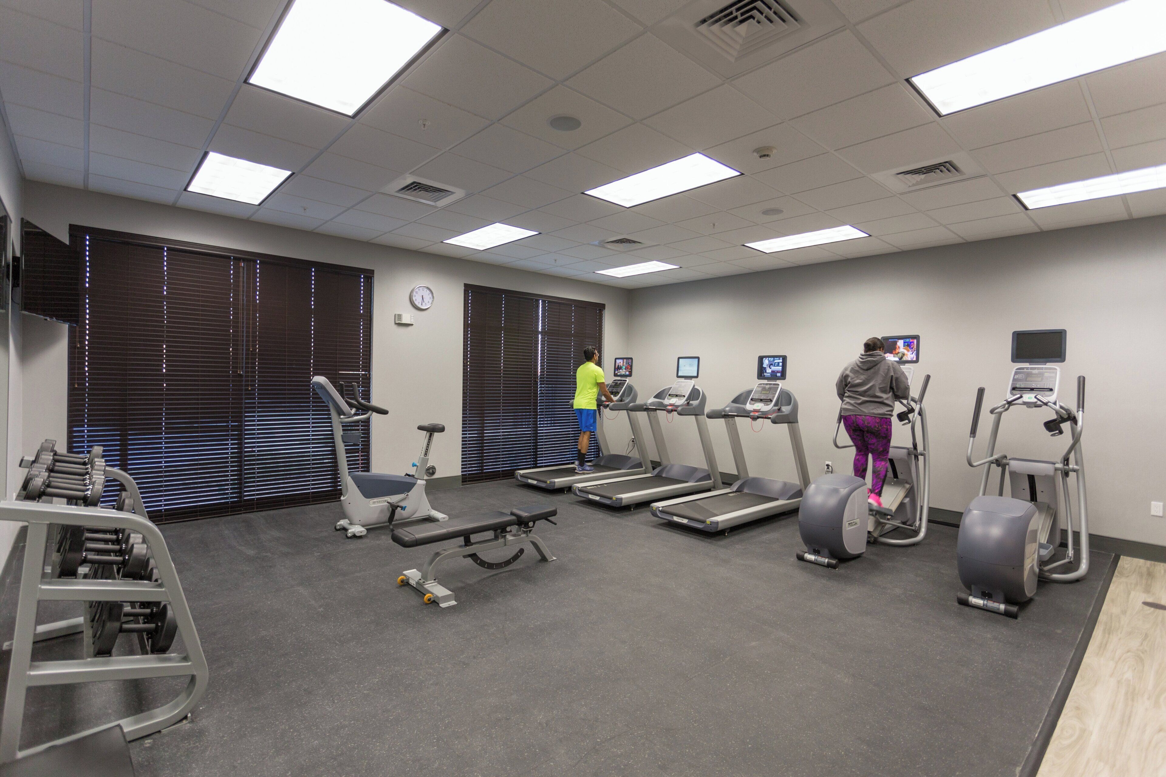 A gym with treadmills, elliptical machines, and a weight bench.