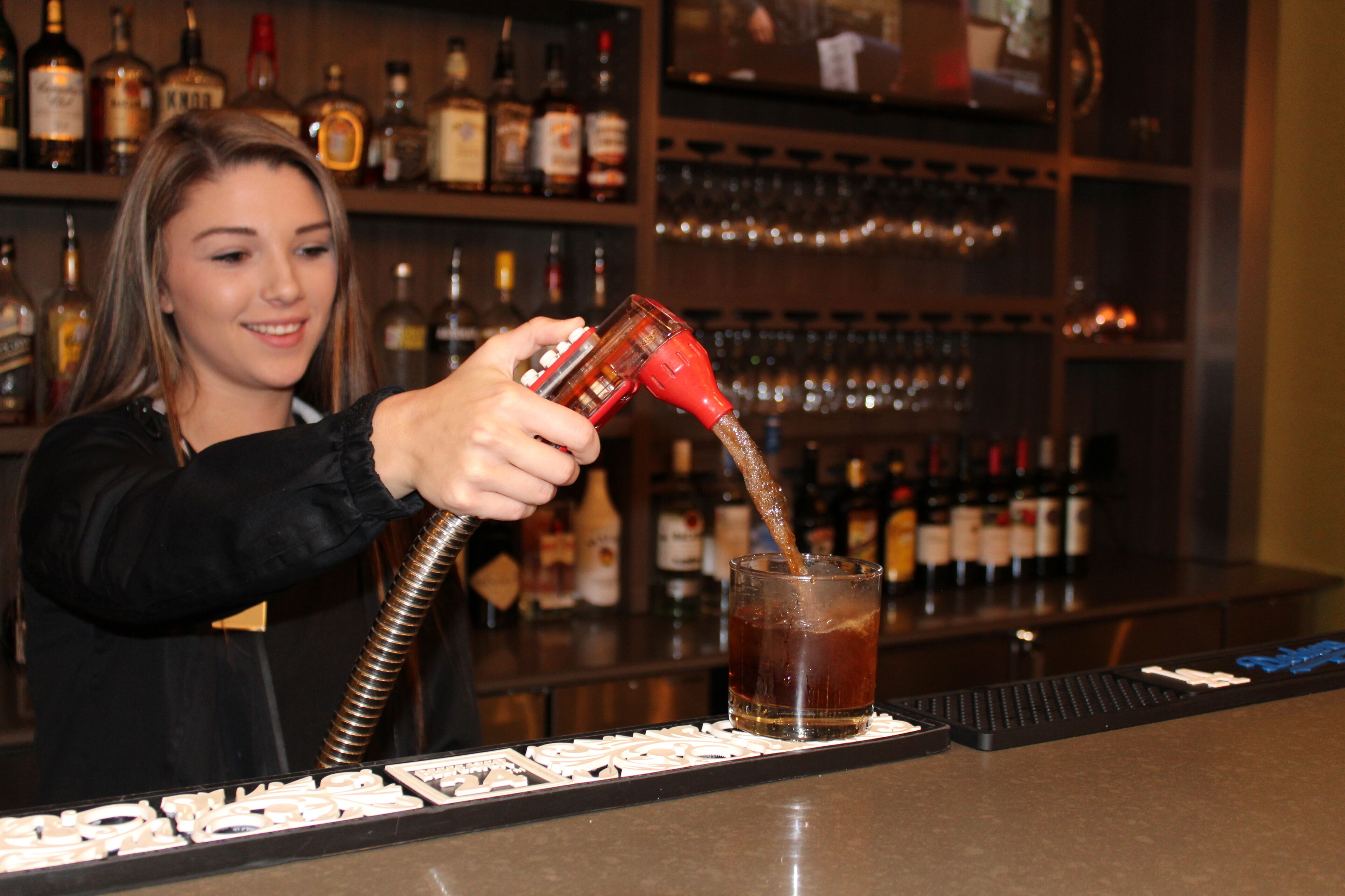 A bartender pouring a drink into a glass.