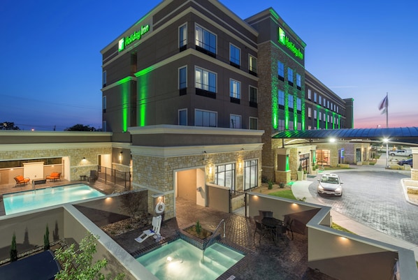 A Holiday Inn hotel with a pool, outdoor seating, and a well-lit entrance. - Holiday Inn San Marcos-Convention CTR Area by IHG (San Marcos)