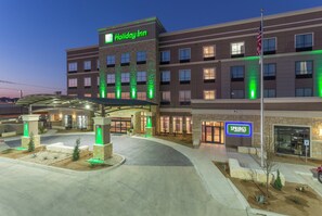 A Holiday Inn hotel with a covered entrance, a Spring's Bistro & Bar, and a flagpole with an American flag. - Holiday Inn San Marcos-Convention CTR Area by IHG (San Marcos)