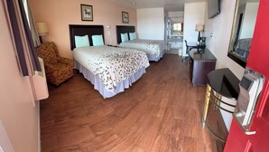Quarto de hotel com duas camas, uma escrivaninha, uma cadeira e uma televisão.