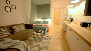 A modern, well-lit living room with a sofa, coffee table, and a kitchen area with a counter and appliances. - IRS ROYAL APARTMENTS - IRS Cztery Oceany (Gdansk)