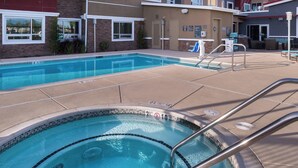 Une piscine avec un jacuzzi, un espace de détente et une terrasse couverte.