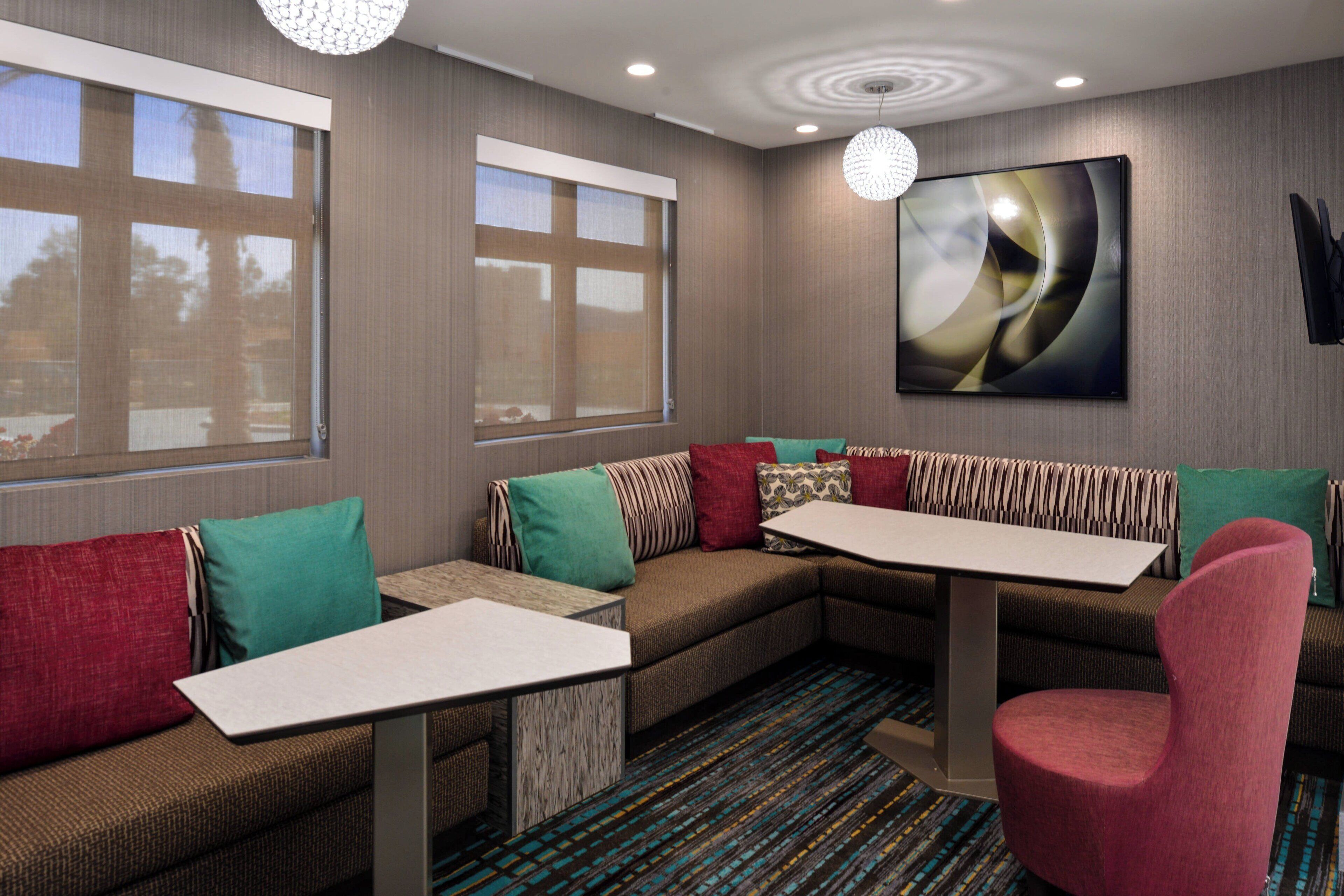 A modern hotel room with a sectional sofa, a small table, and a large abstract painting on the wall.