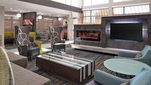 Un salon moderne doté de sièges confortables, d’une cheminée et d’un grand téléviseur à écran plat.