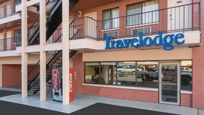 A Travelodge hotel with a red brick facade, large windows, and a Coca-Cola sign. - Travelodge by Wyndham Reno Downtown (Reno)
