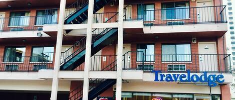 A multi-story building with a travel lodge sign, multiple balconies, and a Coca-Cola vending machine.