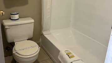 A bathroom with a toilet, a shower, and a towel rack with folded towels.