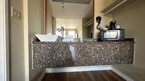 A kitchen with a granite countertop, a sink, a microwave, and a hairdryer. - Travelodge by Wyndham Reno Downtown (Reno)