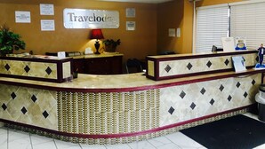 A reception desk with a 'Travelodge' sign, a red lamp, and a plant. - Travelodge by Wyndham Reno Downtown (Reno)